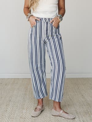 Wide-leg striped pants in navy and cream styled with a simple white tank, woven flats, and stacked stone bracelets — the kind of outfit that looks like you tried just the right amount.