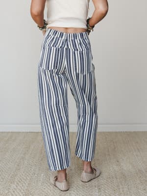 A back-view shot of wide-leg striped pants in navy and cream paired with a cropped white tee and woven flats — the kind of outfit that looks like you tried just enough.
