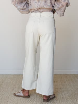 A back-view shot of cream wide-leg jeans styled with a flowy paisley top and neutral sandals — easy, unhurried, and the kind of outfit that looks effortless without trying.