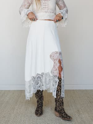 A cream lace two-piece set styled with leopard print cowboy boots and silver turquoise rings — romantic boho dressing that somehow makes a bridal vibe feel totally wearable.