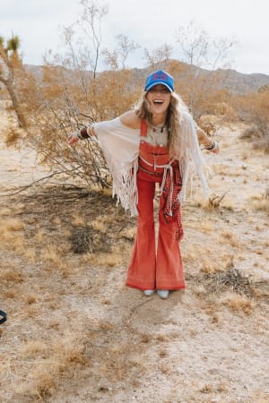 Person in a desert setting wearing a red outfit and blue cap