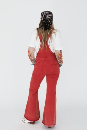 Person wearing red overalls and a black polka dot headscarf on a white background