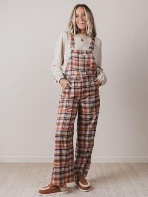 Woman wearing plaid overalls against a plain background