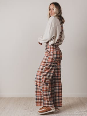 Woman wearing a plaid outfit with suspenders against a plain background