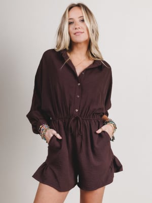 Woman wearing a brown romper against a plain background
