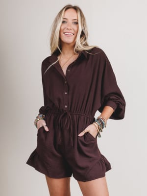 Woman wearing a brown romper against a plain background