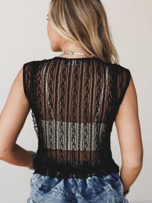 Shot from the back, this sheer black lace knit top has a relaxed, slightly undone feel — styled with acid wash jeans, beaded necklaces, and stacked bracelets for that effortless boho-meets-vintage vibe.