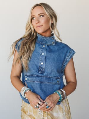 A relaxed denim vest with a mock neck and snap button placket, styled with a golden tie-dye skirt and stacked boho bracelets — the kind of outfit that looks effortless but clearly wasn't an accident.