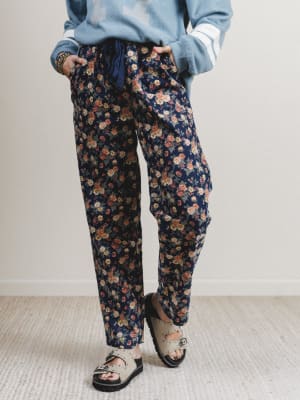 Person wearing floral pants and a light blue sweater on a plain background