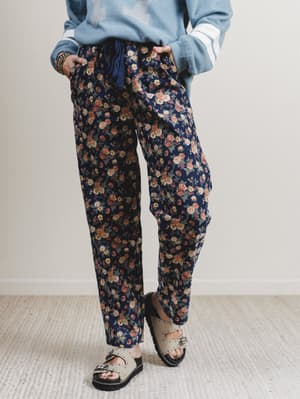 Person wearing floral pants and a light blue sweater on a plain background