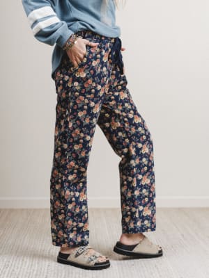 Person wearing navy floral pants with a light blue jacket indoors.
