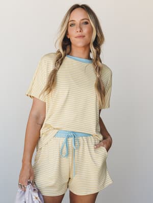 A matching striped tee-and-shorts set in buttery yellow and white with sky blue contrast trim — the kind of outfit that makes a Saturday morning feel like a whole personality.