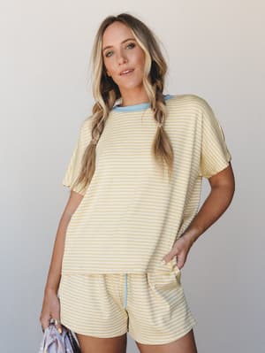 A soft, sun-washed matching set in buttery yellow stripe — the kind of outfit that makes a lazy morning feel intentional, styled with pigtail braids and a peek of sky blue at the neckline.