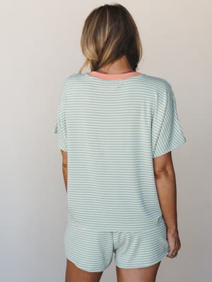 A back-view shot of a matching striped shorts and tee set in soft mint and white, with a warm coral contrast neckline — the kind of set that makes a lazy morning feel like a whole mood.