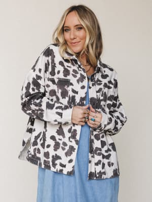 A relaxed, oversized cow print shacket layered over a soft blue midi dress — the kind of effortless outfit that looks like it came together accidentally but definitely didn't.