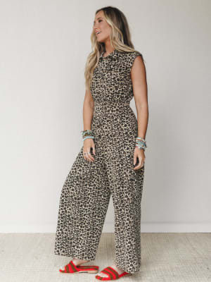 A leopard print wide-leg jumpsuit styled with red crochet sandals and stacked beaded bracelets — the kind of outfit that makes a statement without trying too hard.