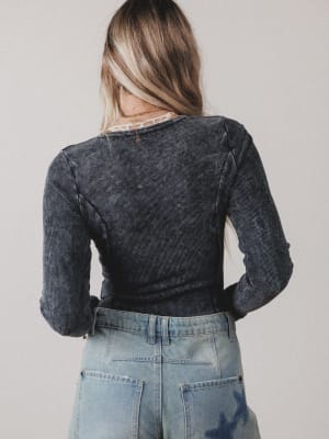 Person wearing a dark denim jacket and light blue jeans on a plain background