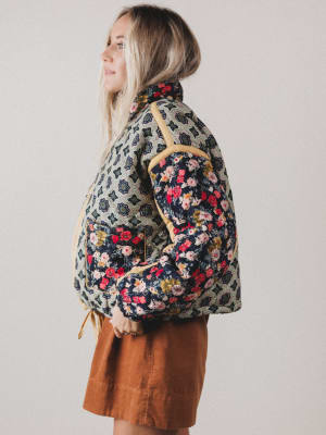 Person wearing a floral-patterned jacket with a neutral background