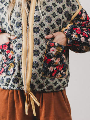 Person wearing a floral patterned jacket with a neutral background