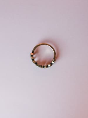 A dainty antique gold stacking ring with small stone settings along the band, photographed from above against a soft blush background — the kind of everyday piece you forget you're wearing until someone asks about it.