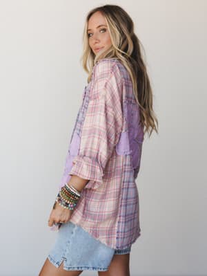 A relaxed plaid flannel top with lace patchwork panels gets the full boho treatment — styled with a denim mini and a wrist full of beaded bracelets, shot in soft studio light with an over-the-shoulder glance that feels effortlessly personal.