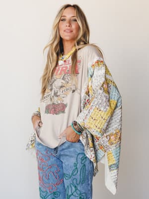 A relaxed, expressive look built around a patchwork poncho draped over a graphic tee and embroidered wide-leg jeans — the kind of outfit that looks like it came together effortlessly but absolutely did not.