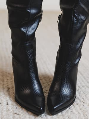 Black leather knee-high boots on a textured surface
