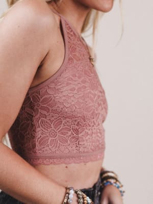 Close-up of a person wearing a pink lace bralette against a neutral background