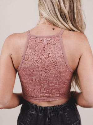 Person wearing a lace bralette top with a neutral background