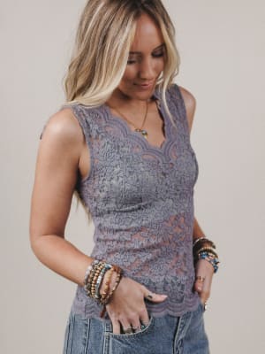 Woman wearing a sleeveless lace top with a neutral background