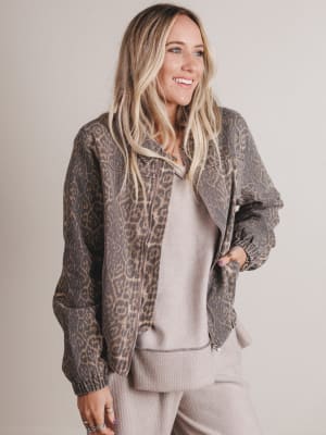 Woman wearing a leopard print jacket over a gray outfit on a plain background