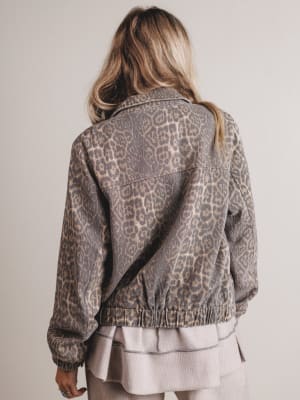 Person wearing a leopard print jacket from behind on a plain background