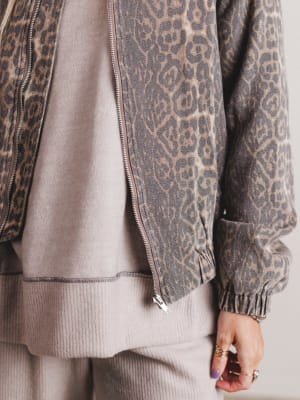 Close-up of a person wearing a gray jacket with a leopard print pattern over a beige outfit.