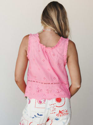 Shot from the back, a pink eyelet tank top with scalloped lace trim and a tiered hem is styled with whimsical illustrated wide-leg pants — playful, summery, and completely its own thing.
