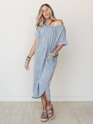 An oversized acid-wash maxi tee dress in soft cloud denim worn off-shoulder with stacked bracelets, layered necklaces, and espadrille flatforms — the kind of effortless outfit that looks like you tried just enough.