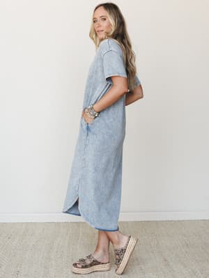 A relaxed maxi tee dress in a washed cloud denim finish, styled with stacked beaded bracelets and leopard print platform sandals — the kind of effortless outfit that looks like you tried just enough.