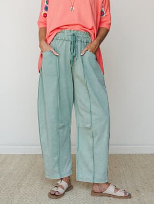 Wide-leg jade green pants with a lived-in washed finish, styled with a coral top with crochet patch detail and white slide sandals — relaxed and colorful in the best way.