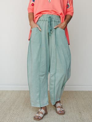 Relaxed, lived-in harem-style pants in a washed jade green paired with a coral top with crochet trim — the kind of effortless combo that looks thrown together but absolutely isn't.