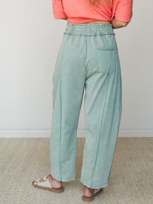 A back-view shot of wide-leg jade green pants with a smocked waistband, paired with a coral crop tee and neutral sandals — easy, relaxed, and ready for a slow Saturday.