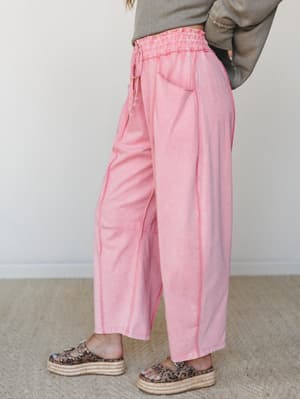 Wide-leg pink pants with a smocked, drawstring waistband styled with a cropped olive sweater and leopard platform sandals — relaxed and a little unexpected in the best way.