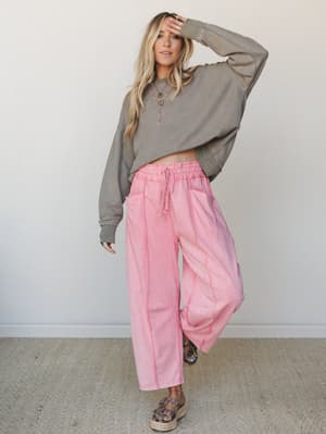 A relaxed, effortlessly cool outfit pairing wide-leg pink drawstring pants with an oversized olive textured sweatshirt — the kind of look that feels pulled-together without trying too hard.