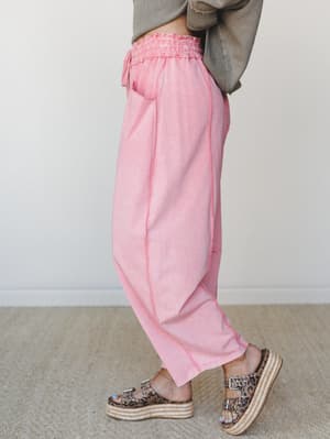 A side-profile shot of wide-leg pants in a washed dusty pink, styled casually with a cropped olive sweater and leopard print platform sandals — the kind of outfit that looks effortless but definitely wasn't an accident.