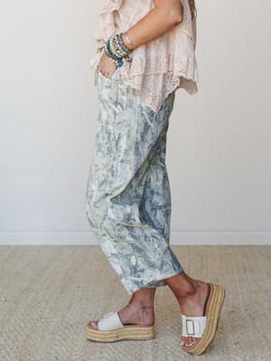 A side-profile shot styled with marble-print relaxed pants, a blush ruffled lace top, and platform espadrille sandals — the kind of effortless outfit that looks like it came together in five minutes but somehow gets compliments all day.