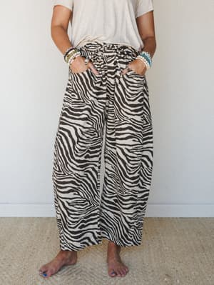 Wide-leg zebra print pants with a self-tie waist styled casually with a tucked cream tee and stacked beaded bracelets — relaxed, expressive, and very much the pants you reach for on a good day.