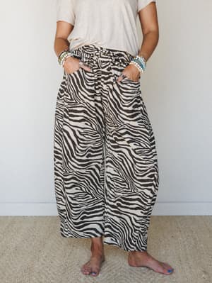 Wide-leg zebra print pants styled with a simple cream tee and stacked beaded bracelets — the kind of outfit that looks like you tried just enough and felt great doing it.