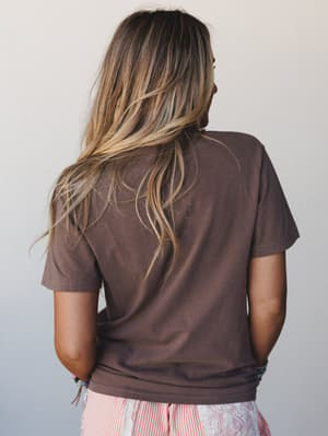 Shot from the back, this relaxed espresso tee pairs with a stripe-and-floral skirt at the hem — easy, lived-in, and the kind of outfit that looks like it came together in two minutes but somehow just works.