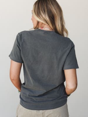 A back view of a washed charcoal graphic tee styled with beaded necklaces and a bracelet stack — the kind of lived-in top that looks like it's been yours for years.
