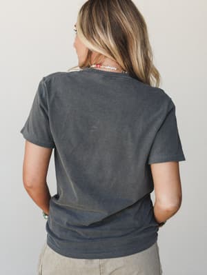 A back view of a washed charcoal graphic tee styled with beaded necklaces and a bracelet stack — the kind of lived-in top that looks like it's been yours for years.