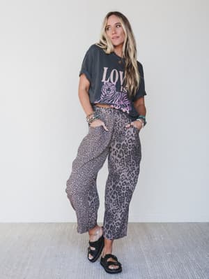 Woman wearing a graphic t-shirt and leopard print pants against a white background