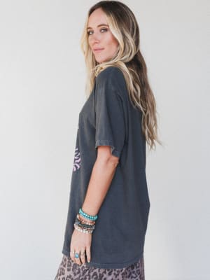 Woman wearing a dark gray t-shirt with a graphic design on a plain background